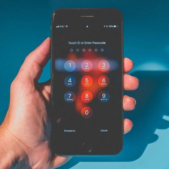 A person's hand holds a smartphone displaying a passcode screen.