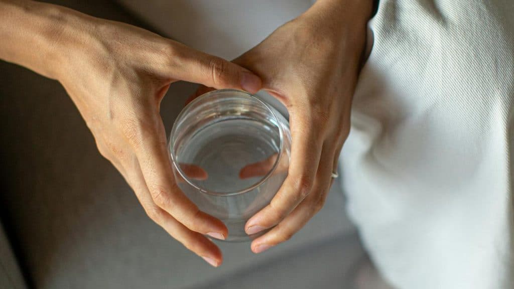 A person holding a glass of water with both hands.