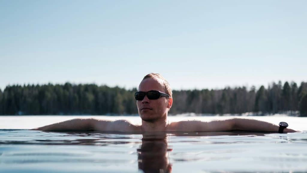 A man wearing sunglasses relaxing in water outdoors.