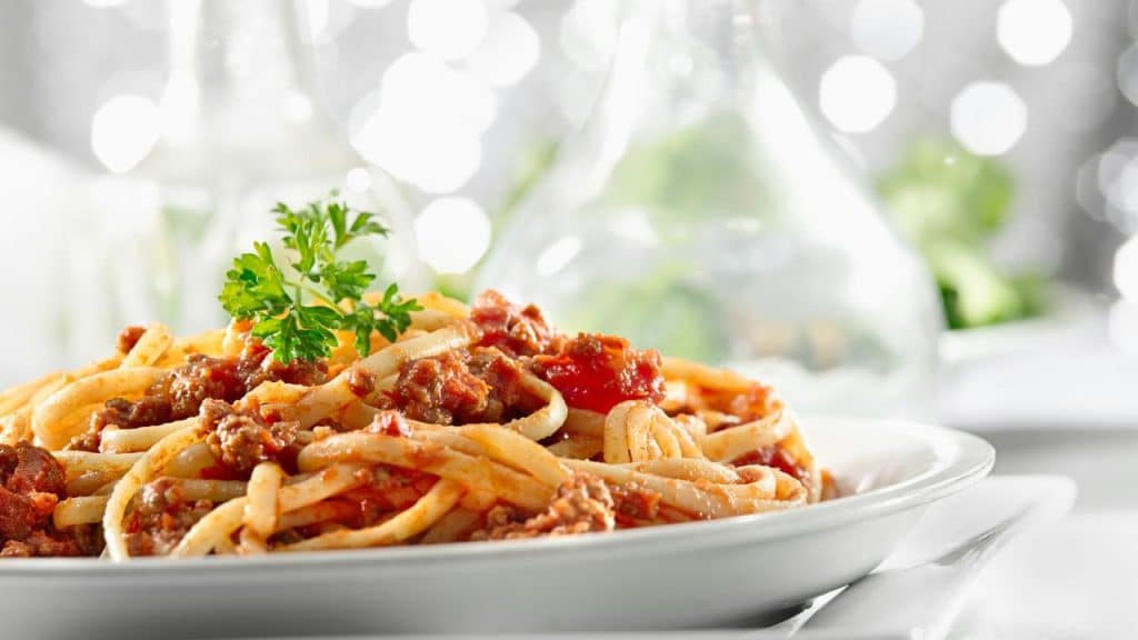 A plate of spaghetti bolognese garnished with parsley.