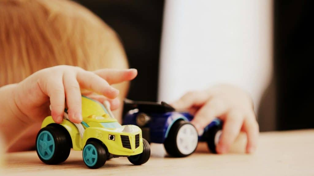 A young child playing with toy cars on a table.