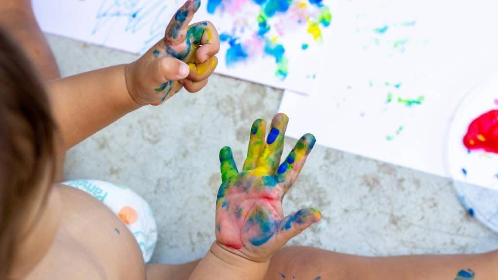 A toddler with paint-covered hands creating art.