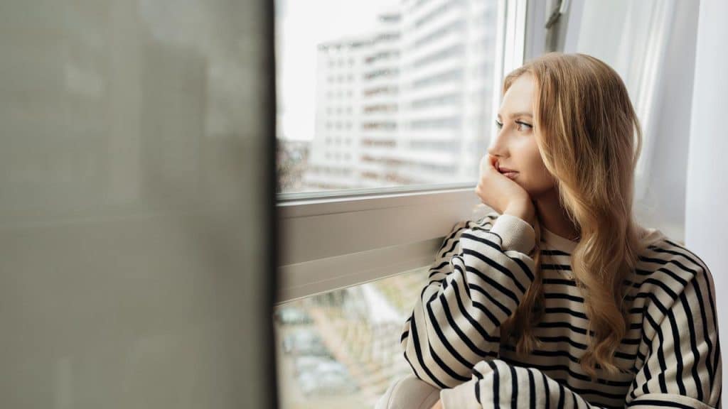 A woman in a striped sweater looking out a window.