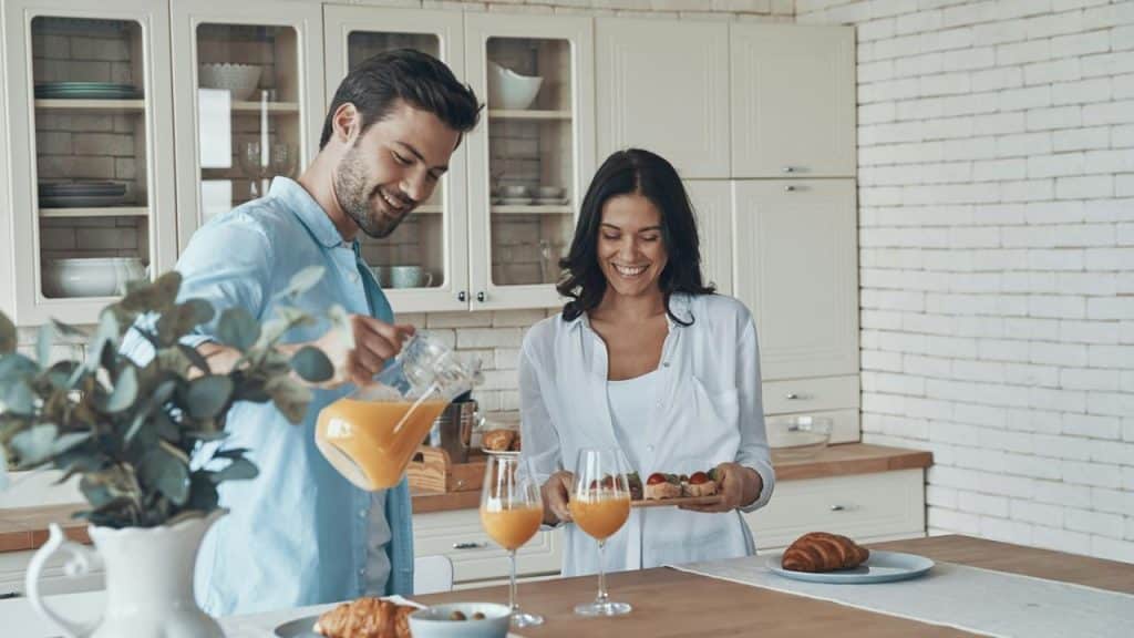 A couple preparing breakfast in a kitchen.