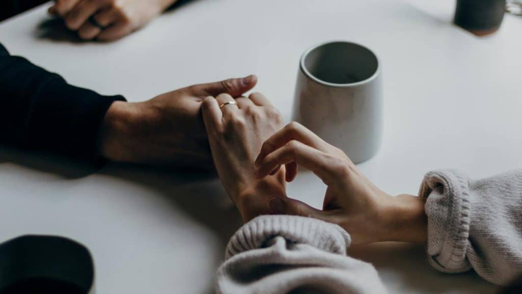 A couple holding hands at a table.