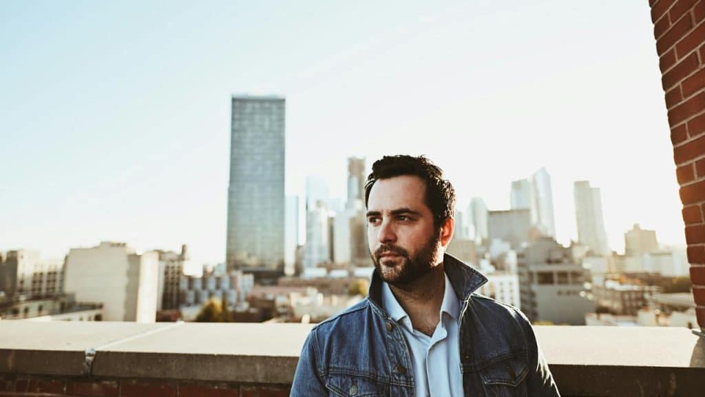 A man in a denim jacket on a rooftop.