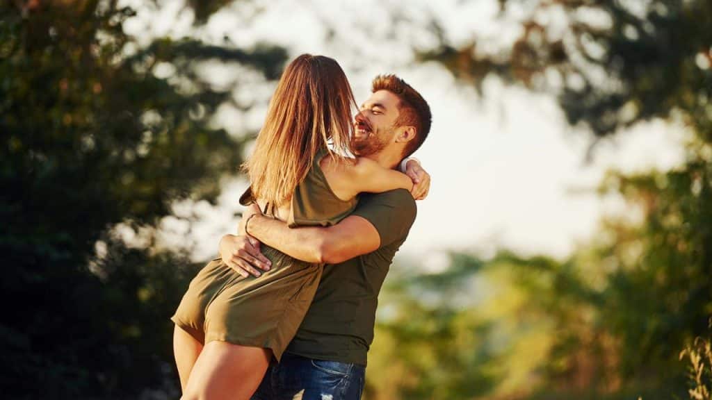 A couple embracing outdoors in a joyful moment.