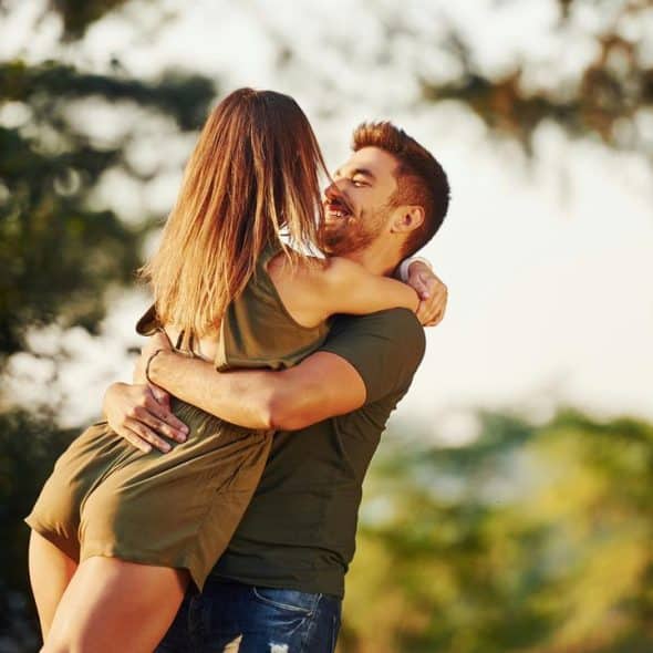 A couple embracing outdoors in a joyful moment.