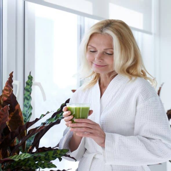 A beautiful mature woman drinking green juice