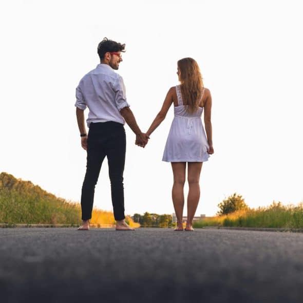 A man and woman holding hands in the middle of the road