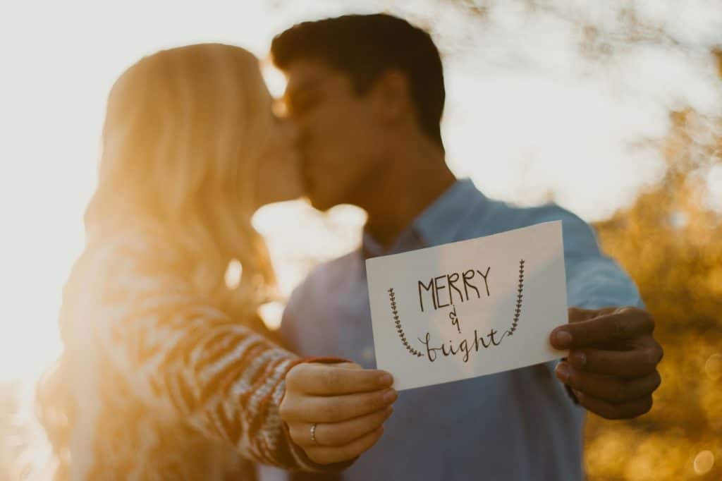 A man and woman holding a sign while kissing