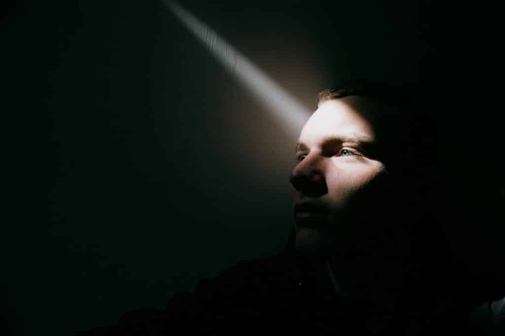 A man at the dark with spotlights on his eyes