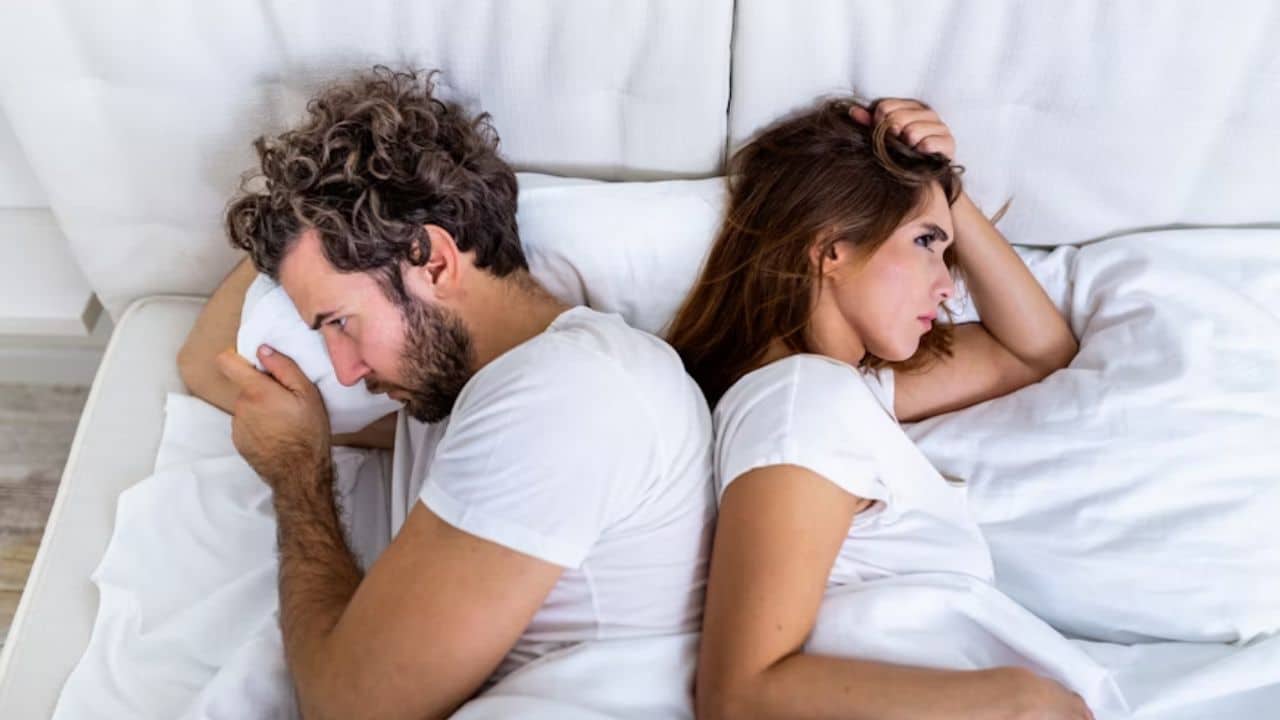 Emotionally distant couple lacking physical intimacy in bed.