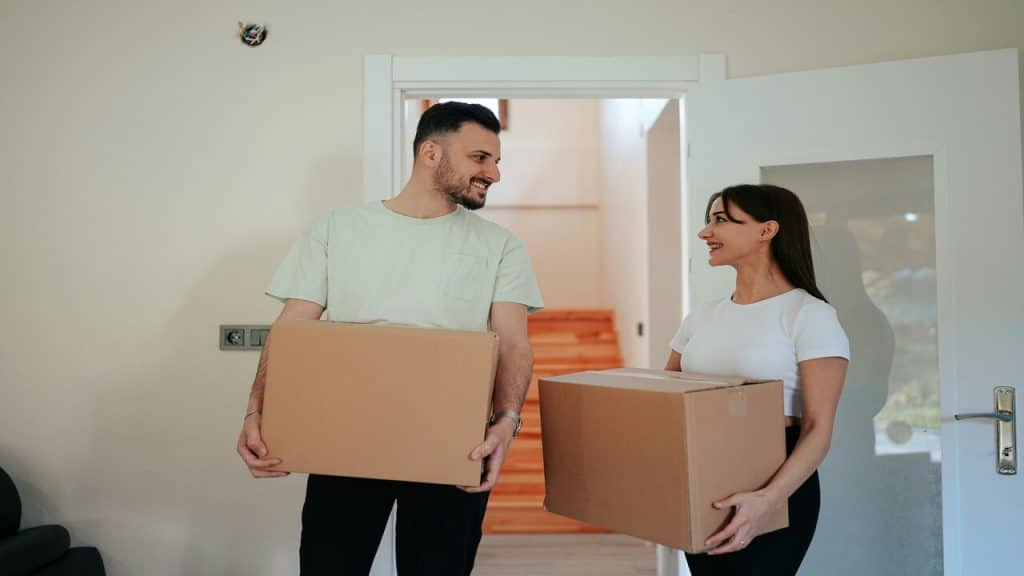 A couple holding moving boxes.