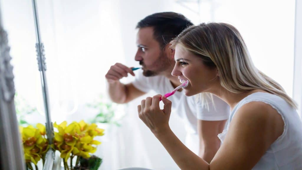 A couple brushing their teeth together.