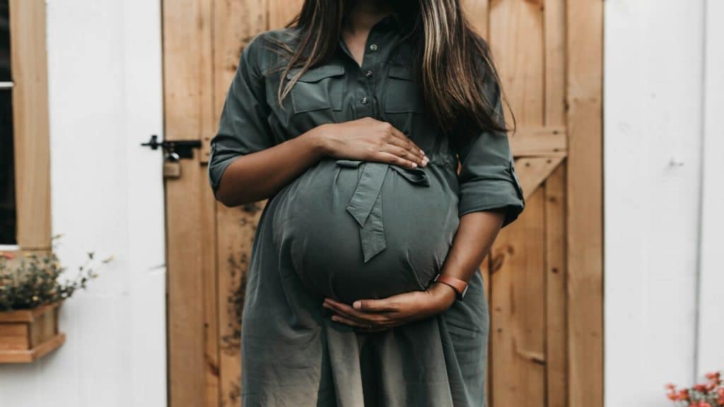 A pregnant woman wearing a green dress.