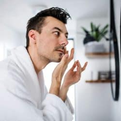 A man looking at his skin through mirror