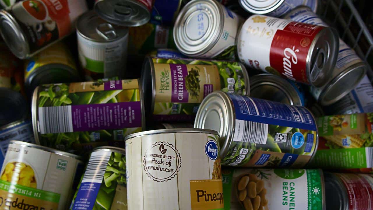 A pile of assorted canned foods, including vegetables, beans, and soups.