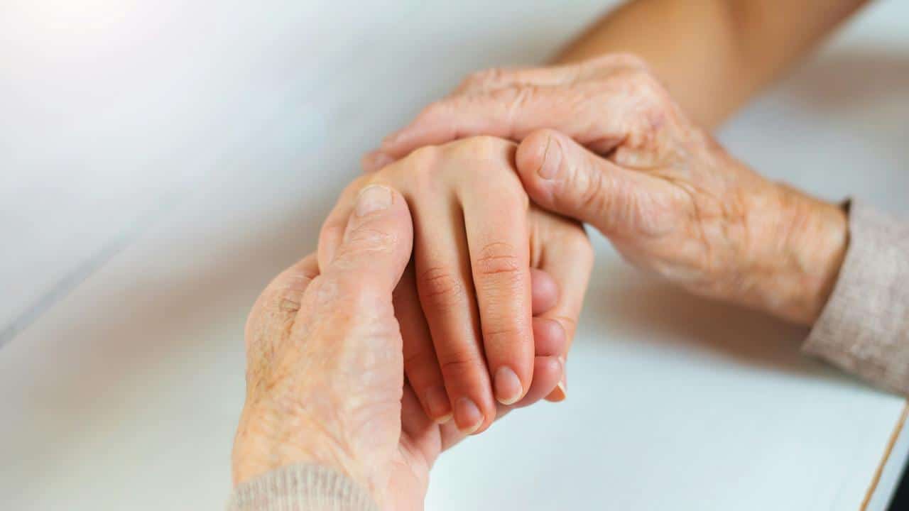 An elderly person holding a younger person’s hand.