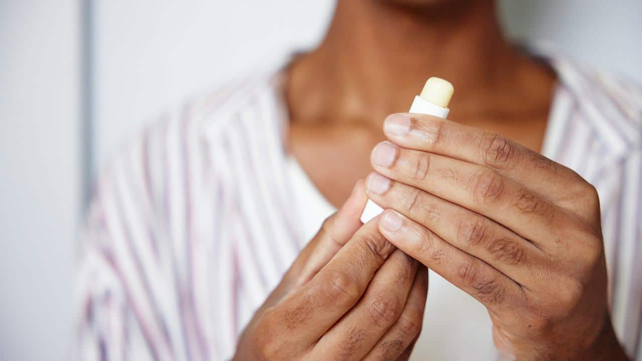 A person holding a tube of lip balm.