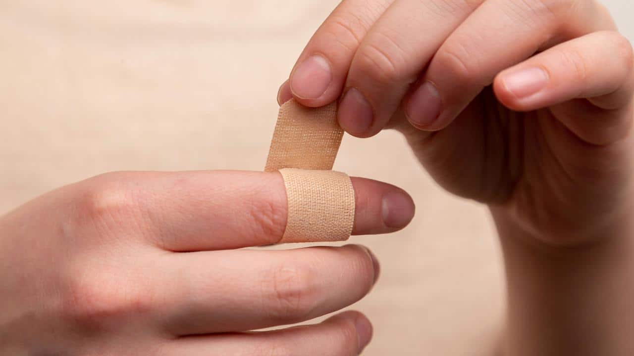 A person applying a bandage to their finger.