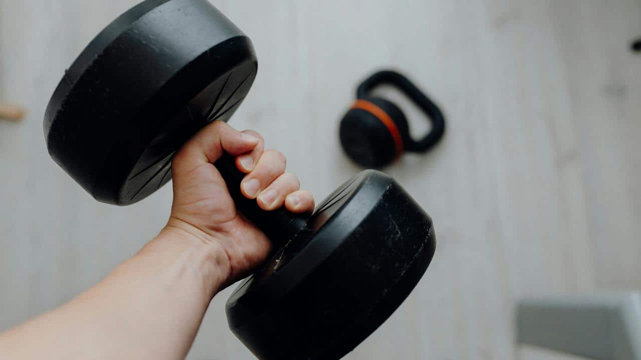 A person holding a black dumbbell.