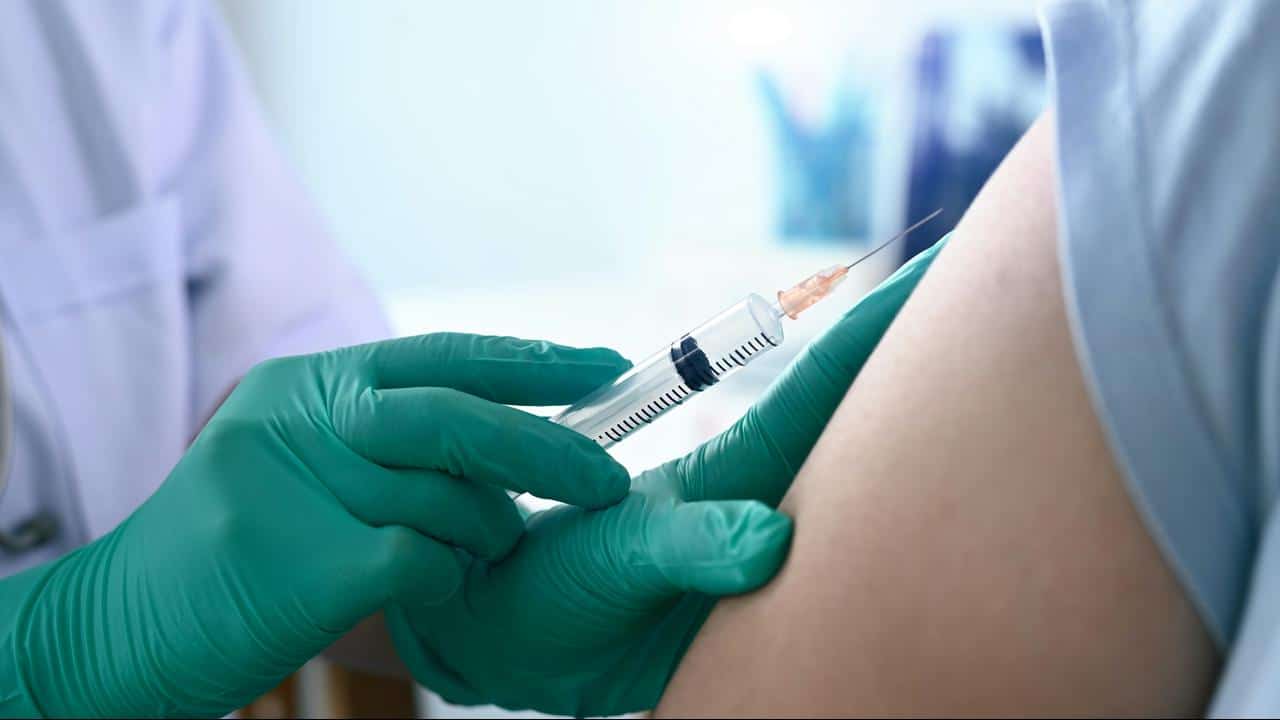 A healthcare worker giving an injection in a patient’s arm.