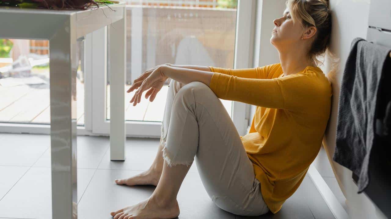 A woman sitting on the floor looking distressed.
