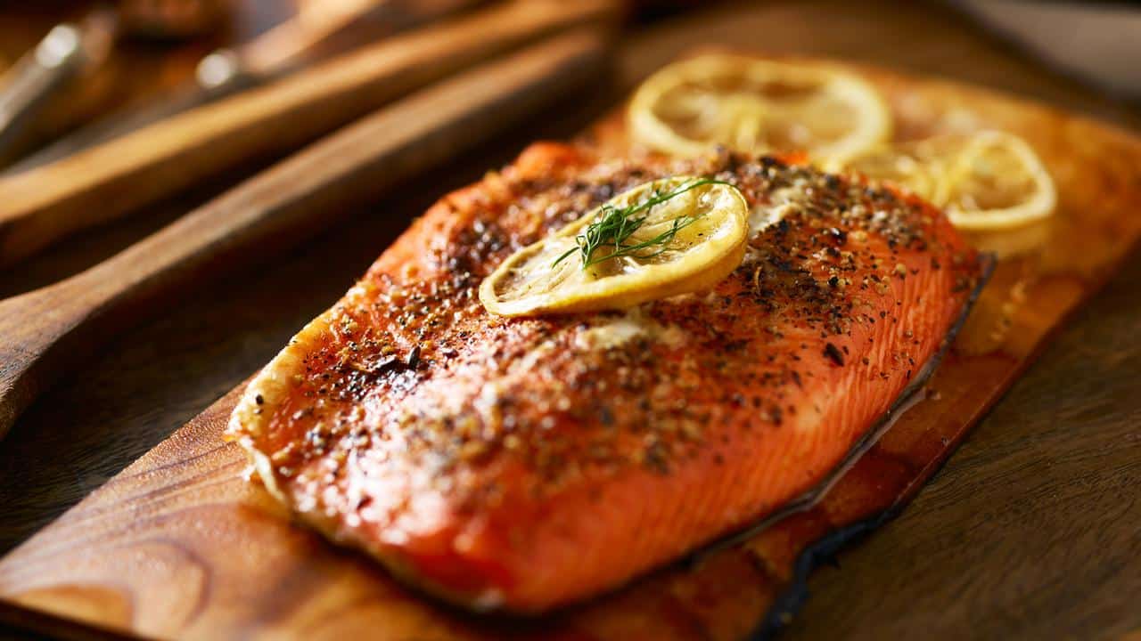 A grilled salmon fillet topped with lemon slices and herbs.