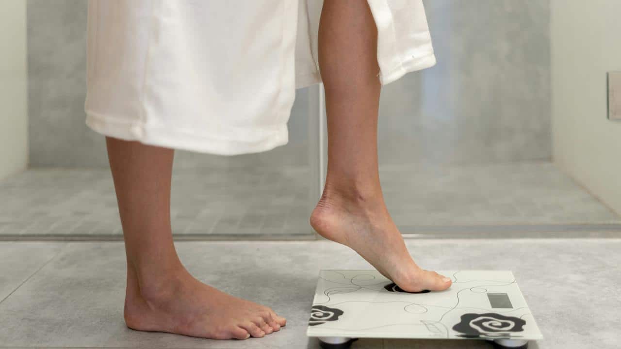 A person stepping onto a bathroom scale to check their weight.