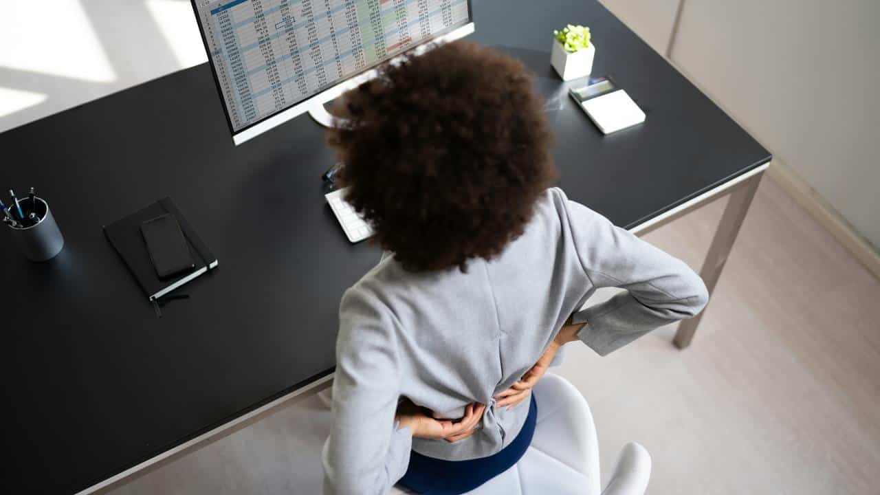 A woman with back pain at her desk.