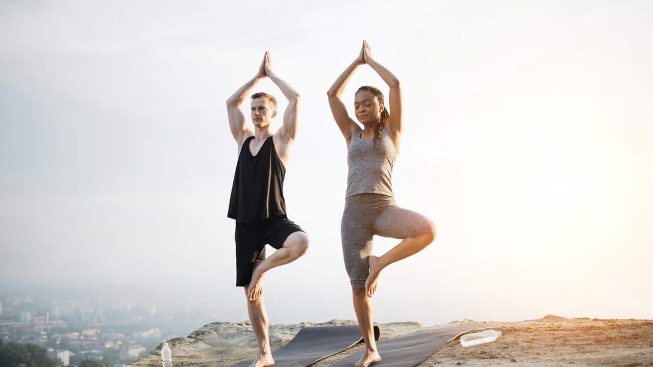 A man and woman doing yoga outdoors.