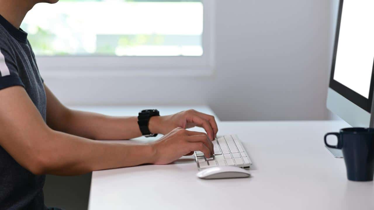A man typing on a desktop keyboard.