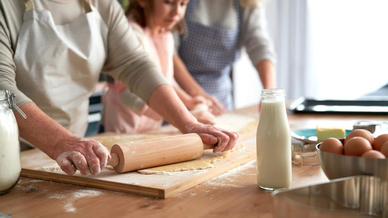 A family rolling dough together in the kitchen.
