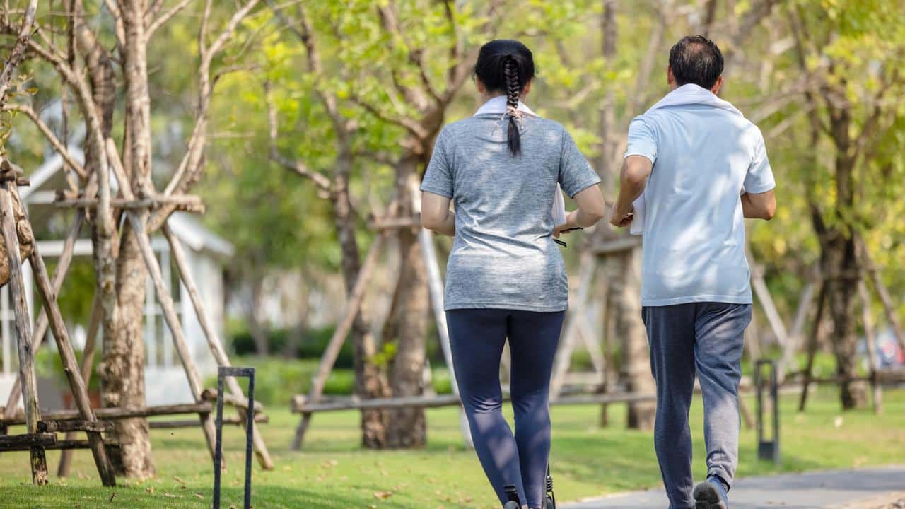 A couple walking together in a park on a sunny day.