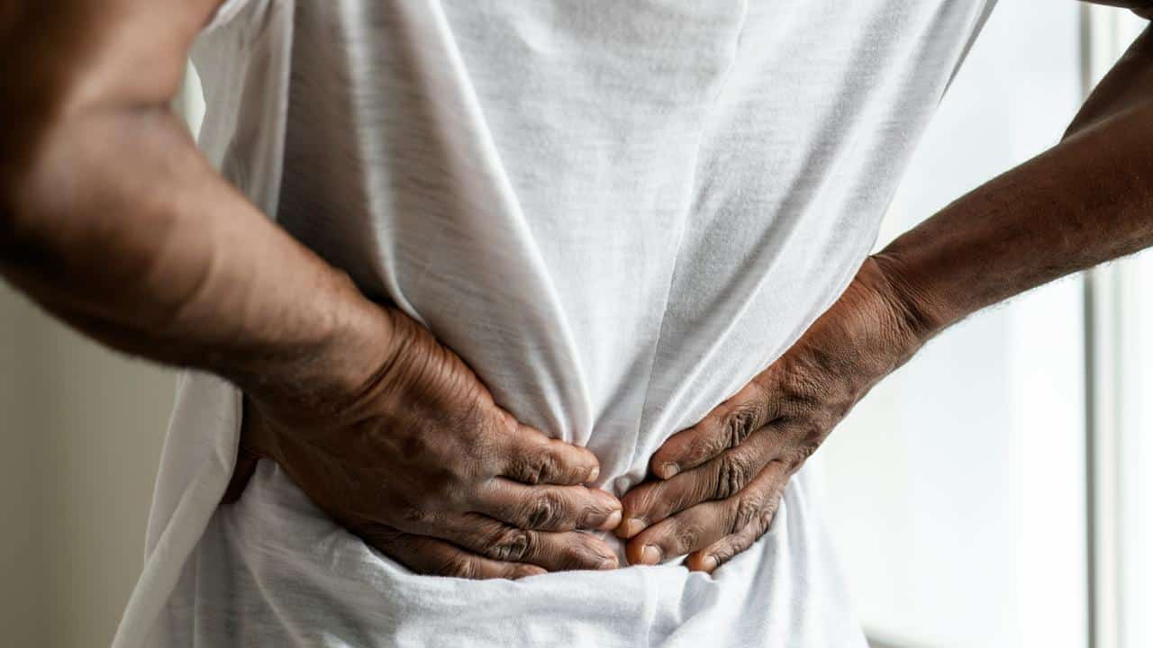 A person holding their lower back in pain.