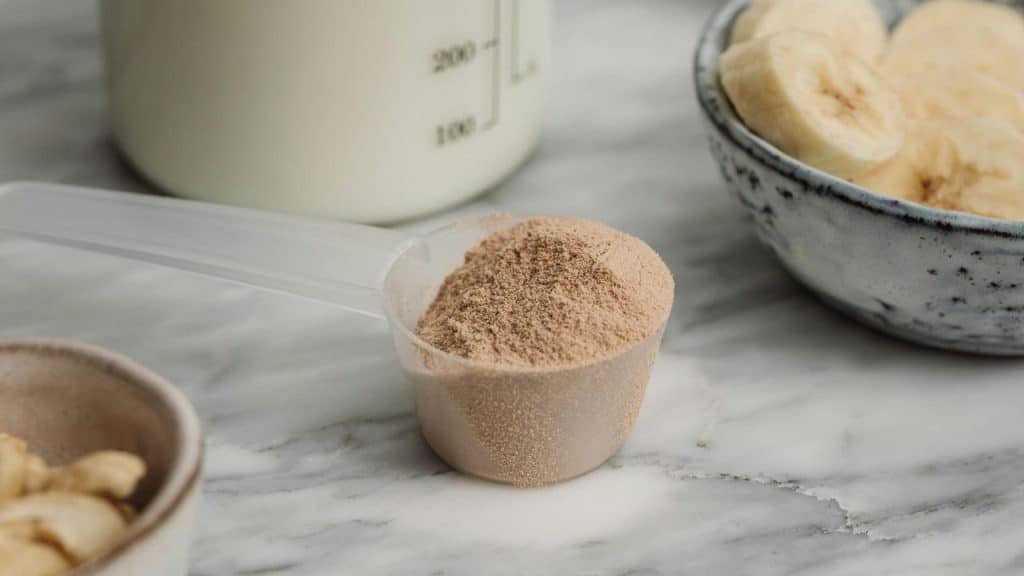 A scoop of protein powder with bananas and milk.