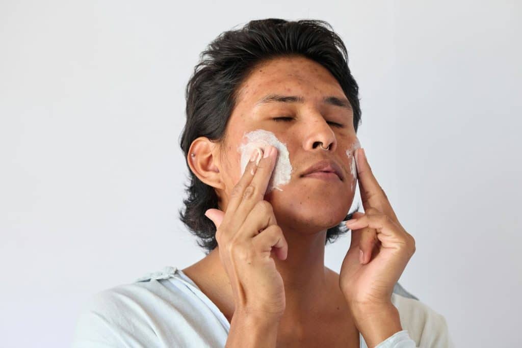 A man using exfoliating cream on face