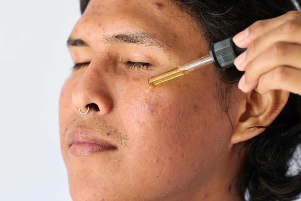 A man using serum on his face