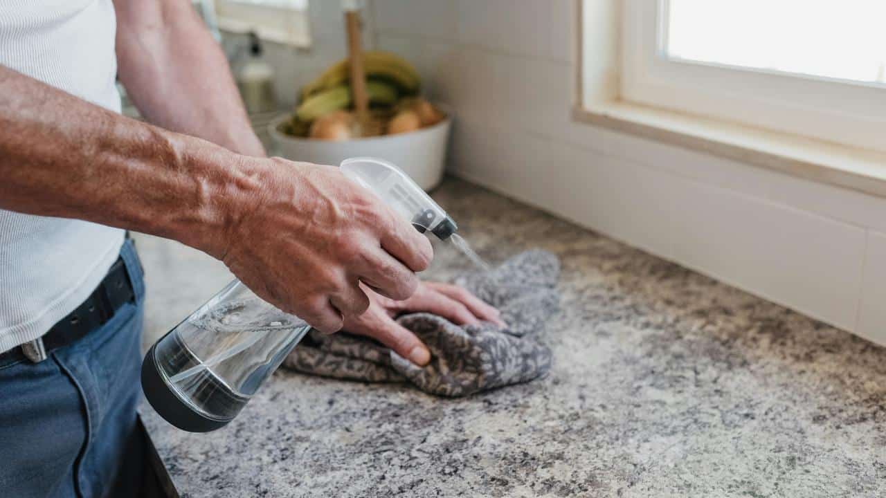 A person cleaning a granite countertop.