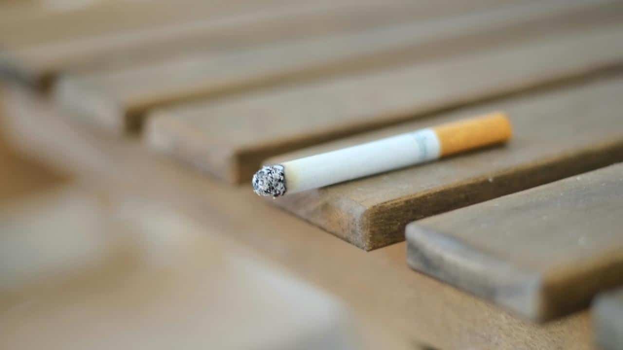 A lit cigarette on a wooden surface.
