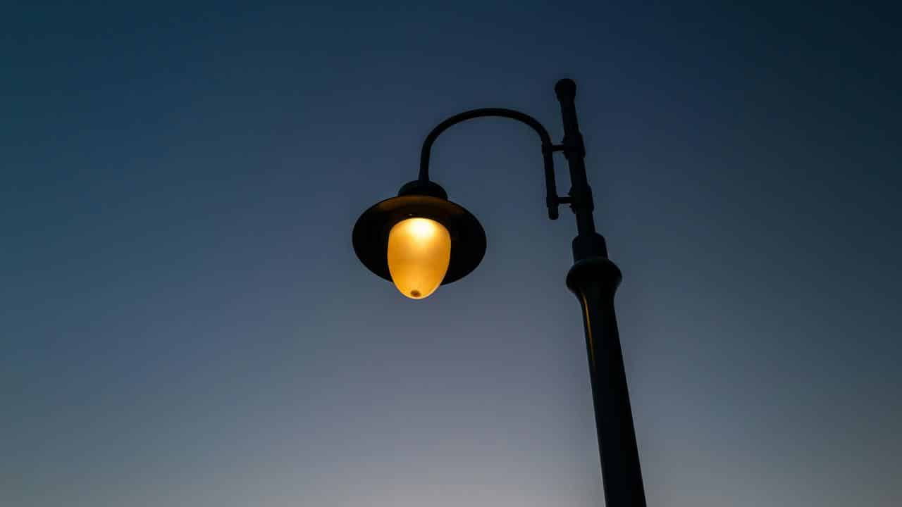 A lit streetlamp against the evening sky.