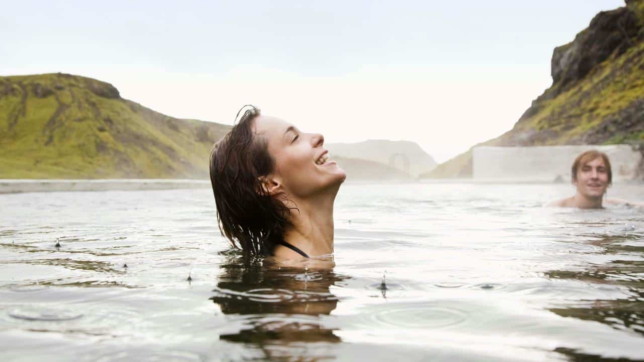 A woman smiling while swimming outdoors.
