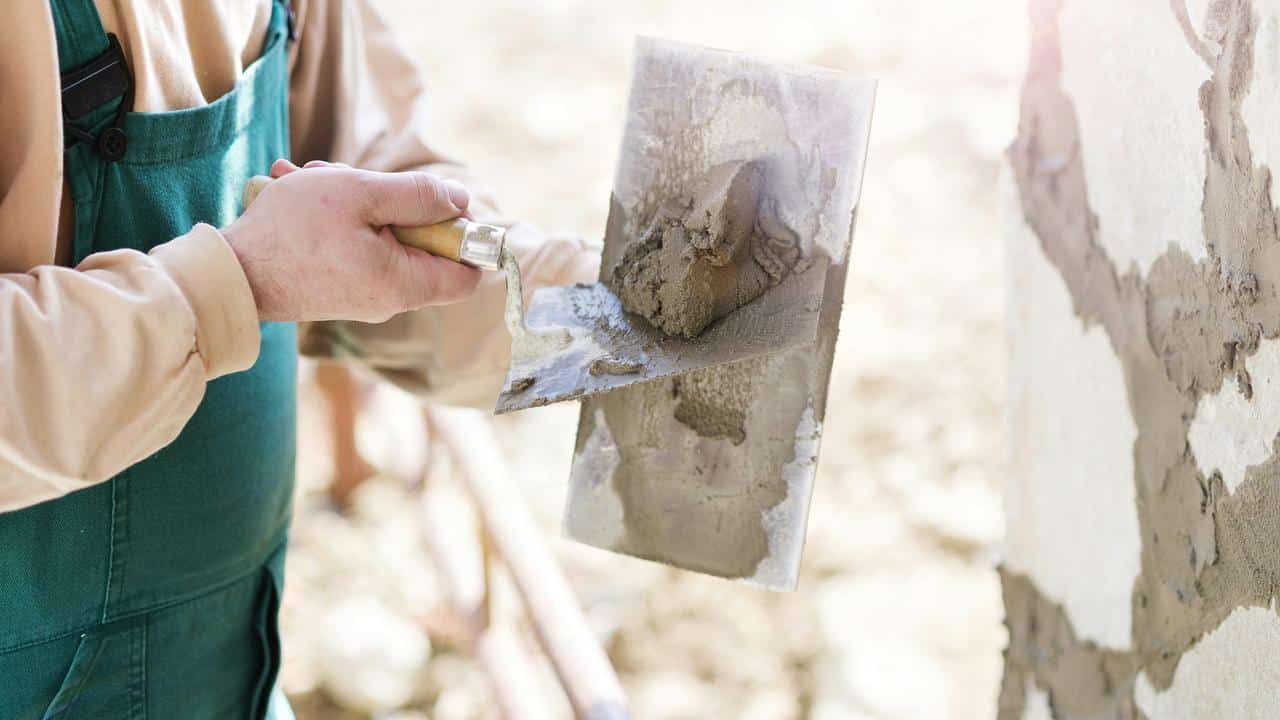 A construction worker applying cement to a wall.