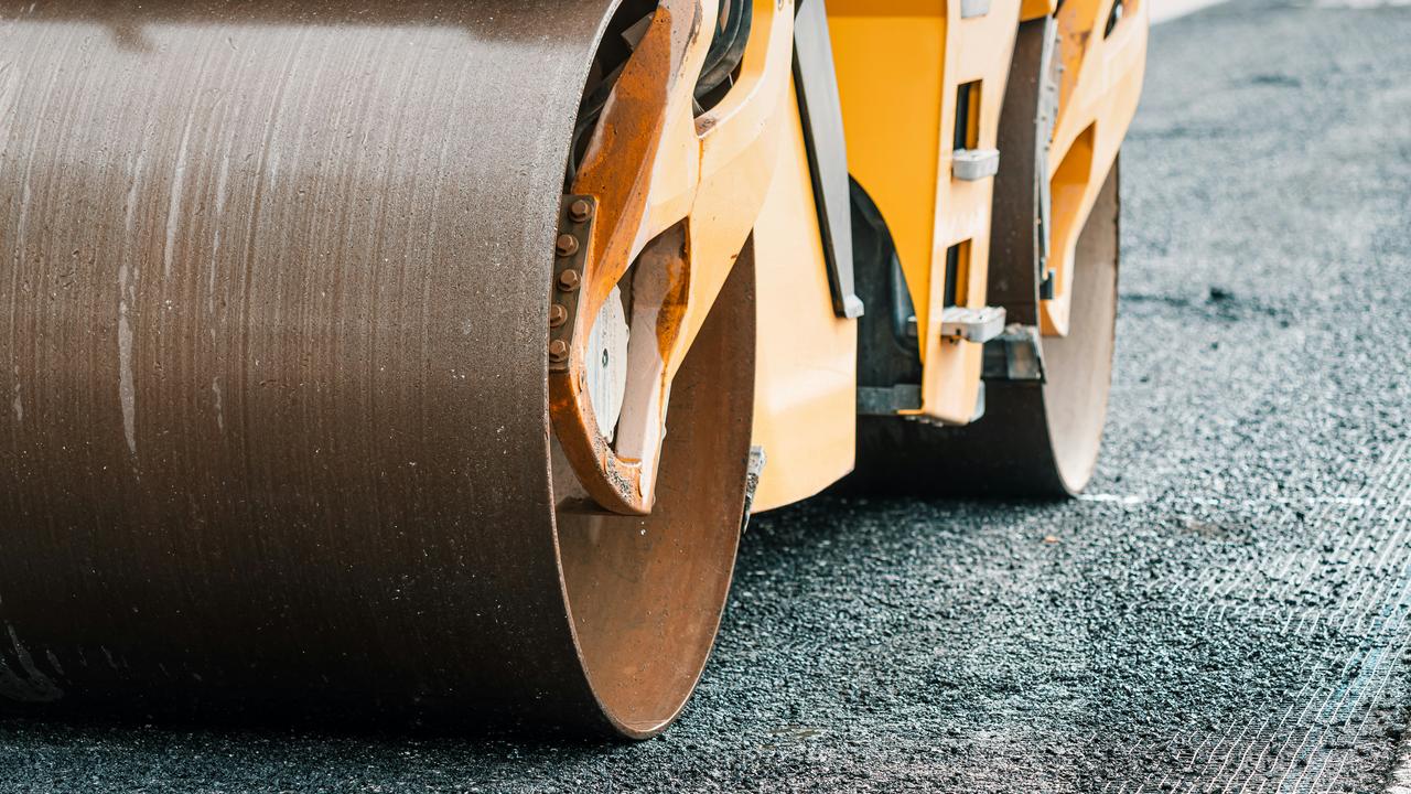 A close-up of a road roller on asphalt.