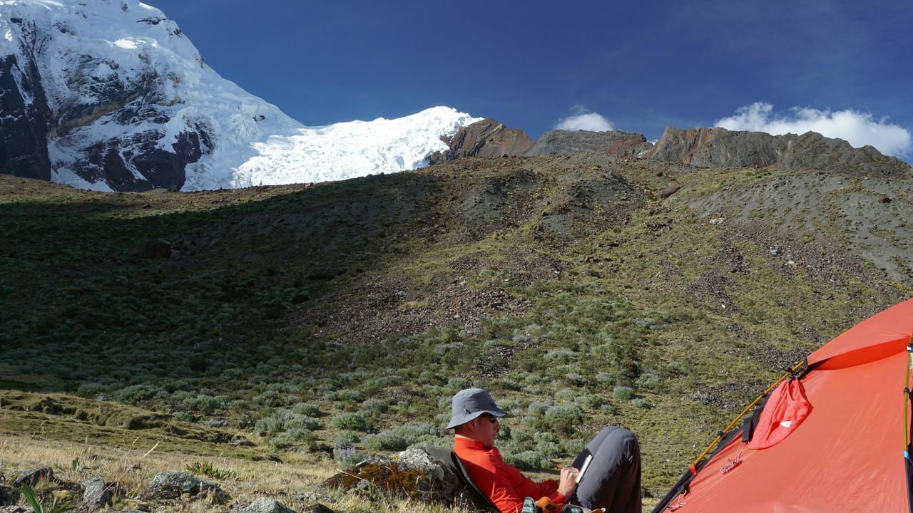 A camper relaxing beside a tent in the mountains.