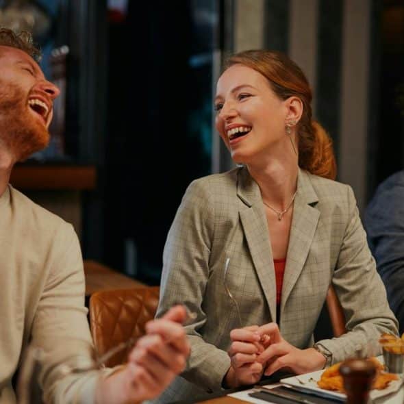 A man and woman laughing together while dining at a restaurant.