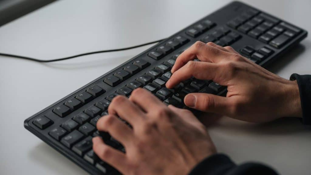 A person typing on a full-sized keyboard.