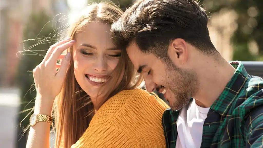 A smiling couple sharing a joyful moment outdoors.