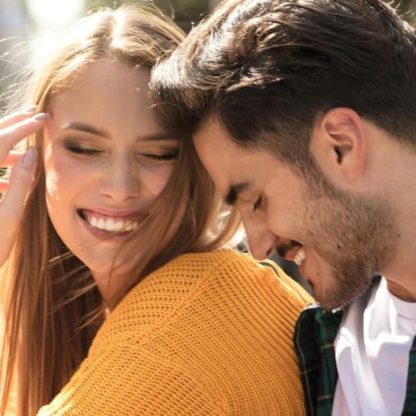 A smiling couple sharing a joyful moment outdoors.